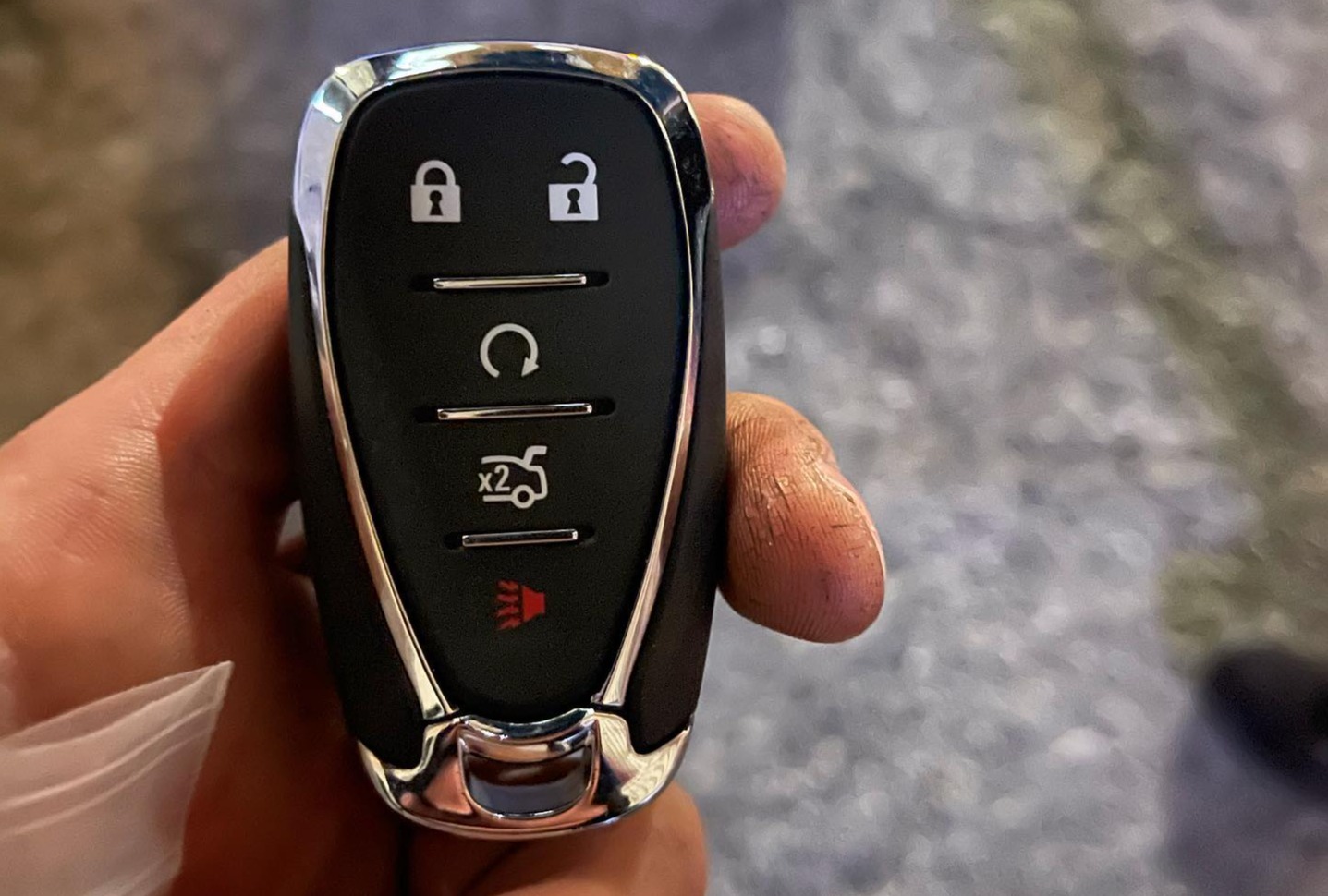 A hand holding a Chevy key fob